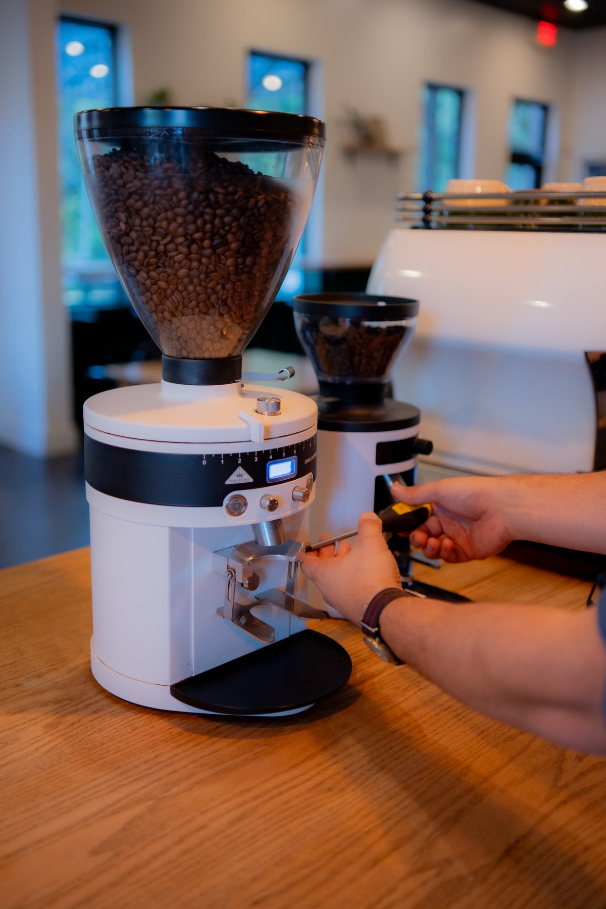 A side-angled shot of a technician servicing a coffee grinder