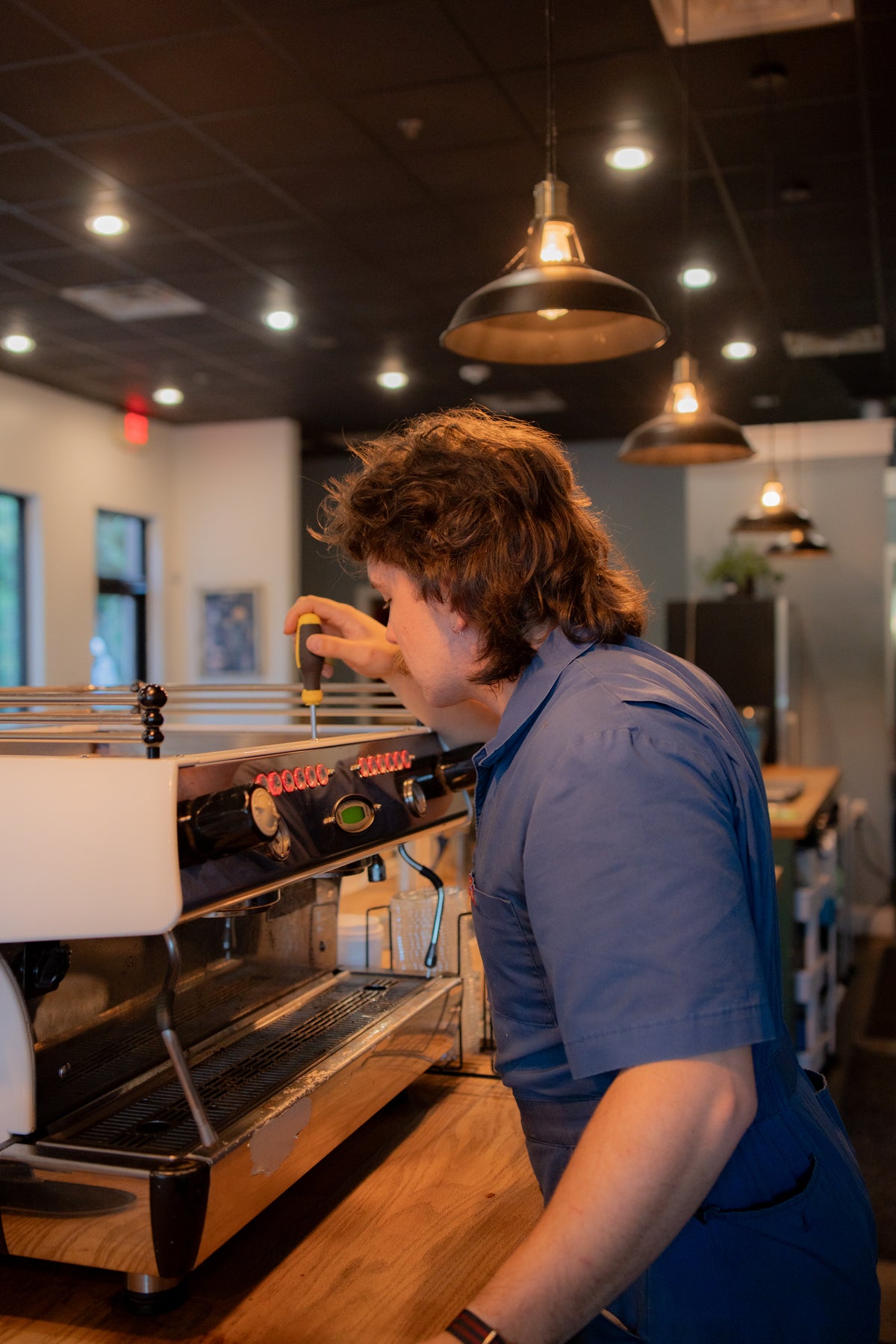 Cold Spell technician besides a commercial espresso machine in a cafe