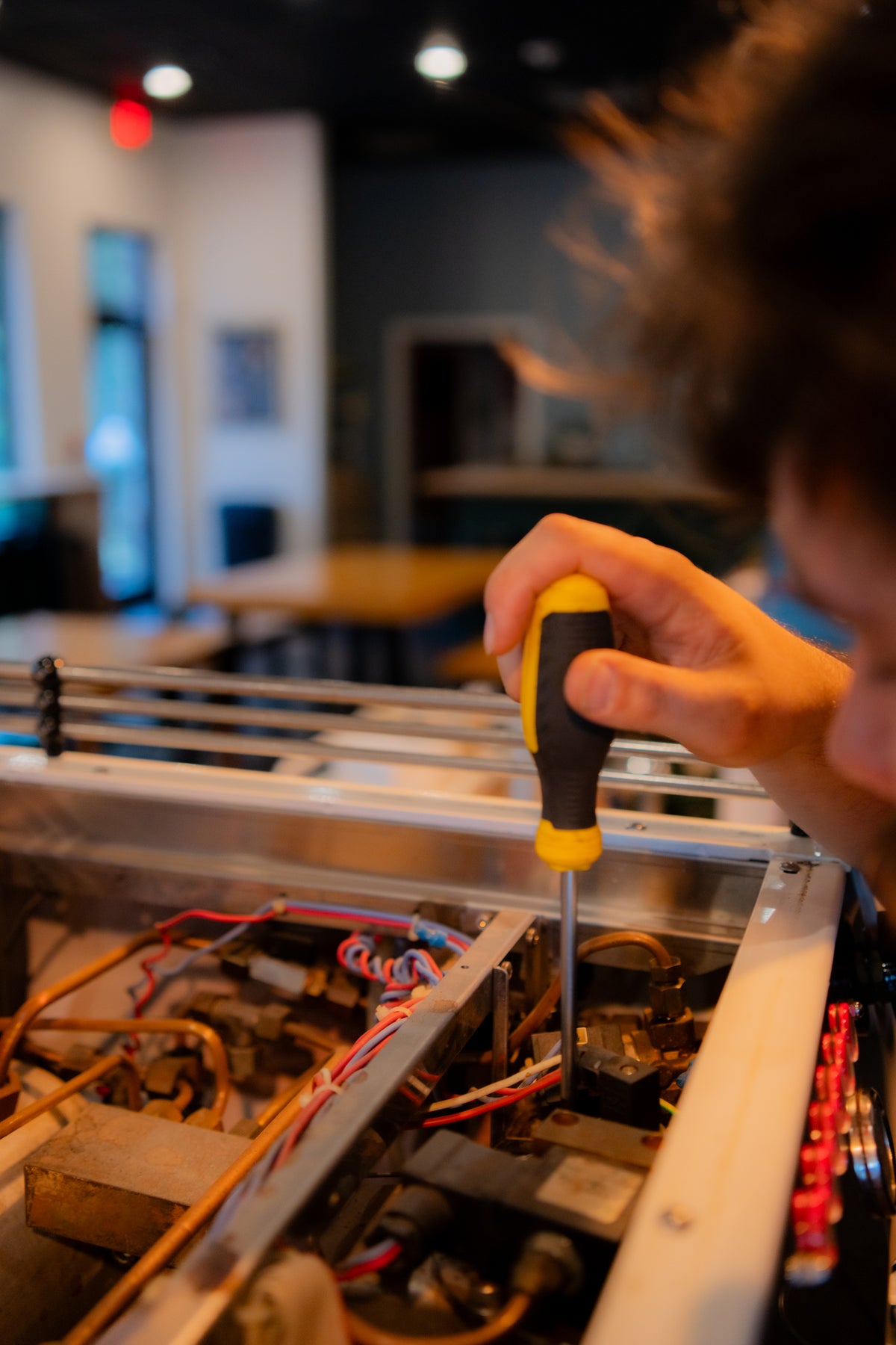 Close up shot of a coffee technician repairing electrical wiring for an espresso machine.