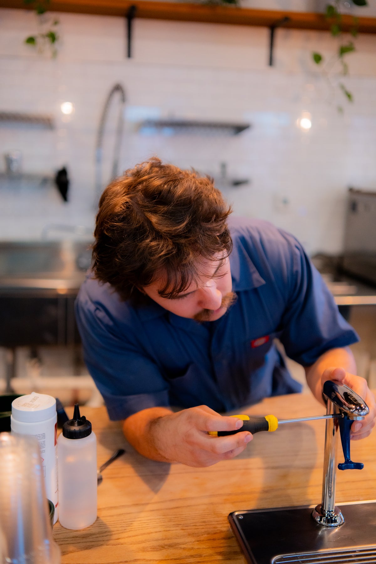 Coffee technician servicing a water filtration system on top of coffee bar